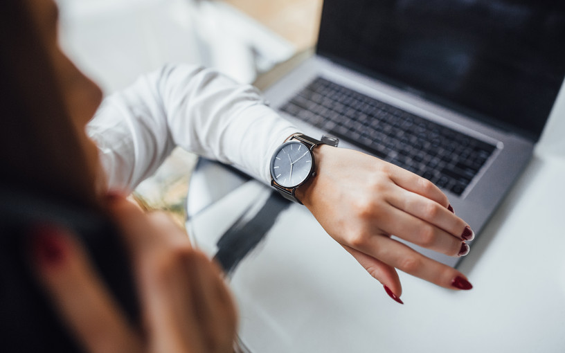 Kvinde kikker på sit arbejdsur ved pc